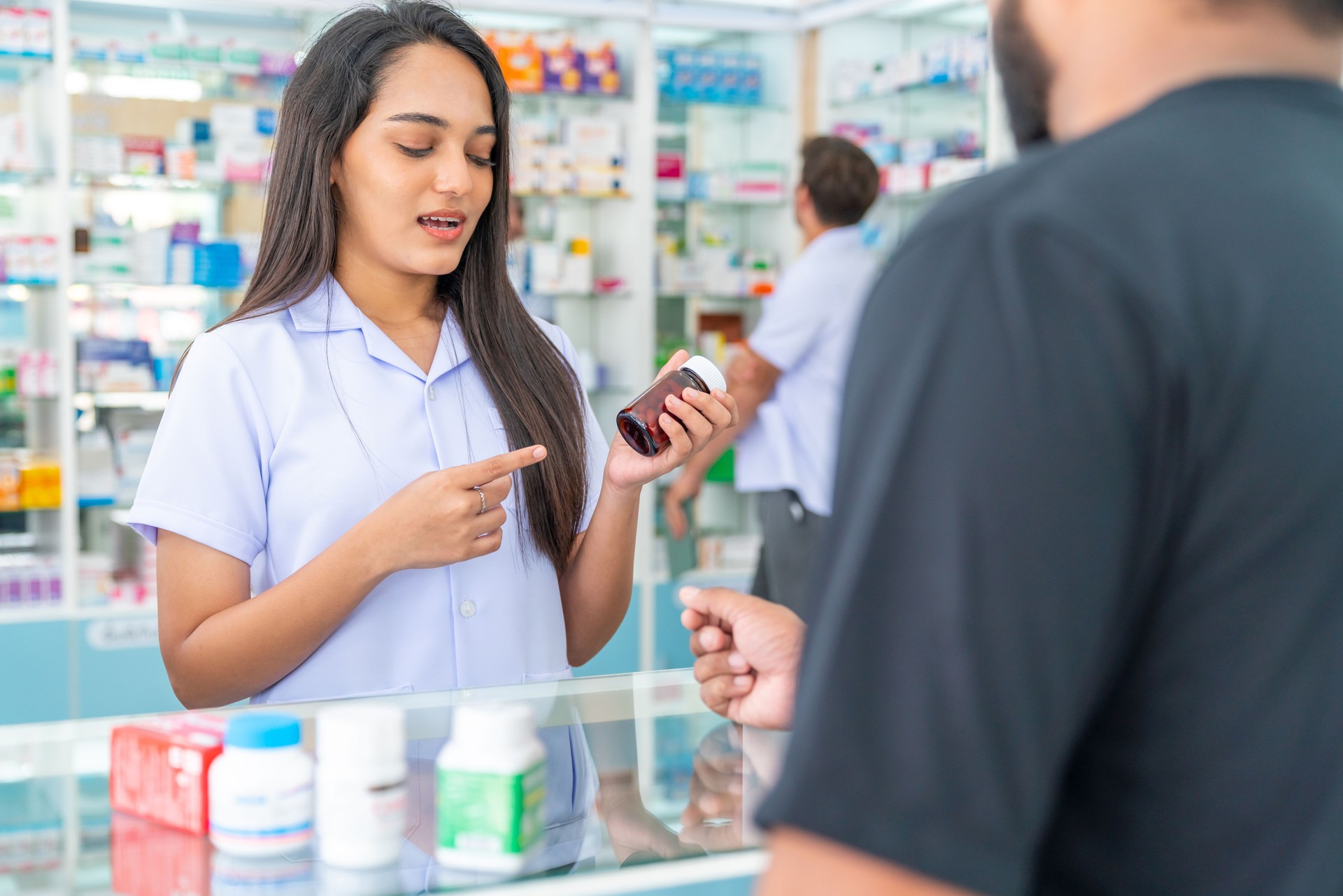 La farmacéutica india explica sobre medicamentos y suplementos al cliente masculino en la farmacia.