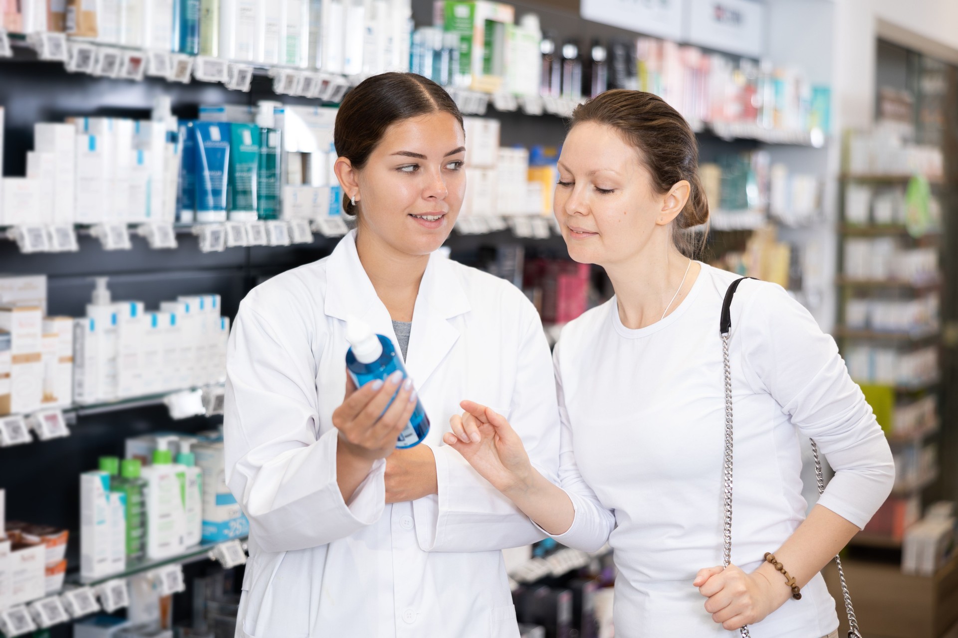 Mujer farmacéutica ayuda a la clienta a elegir el producto cosmético